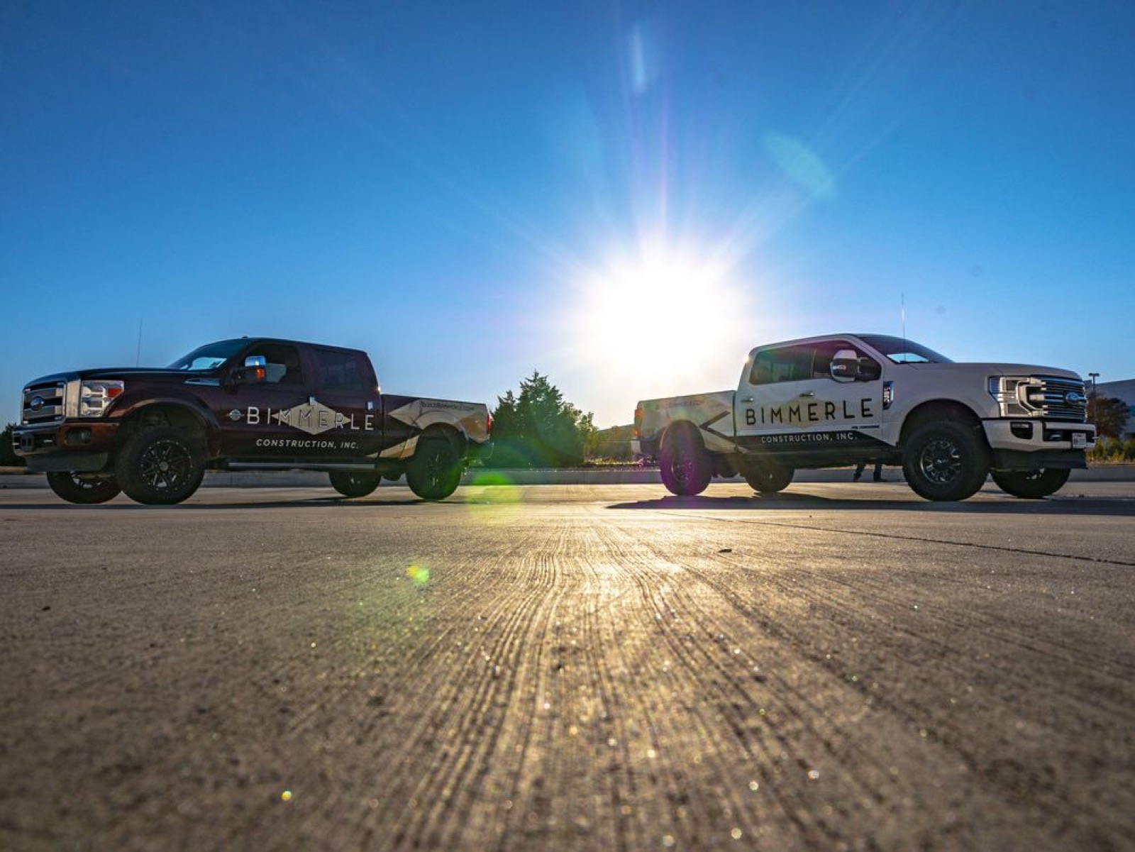 Two wrapped work trucks at sunset