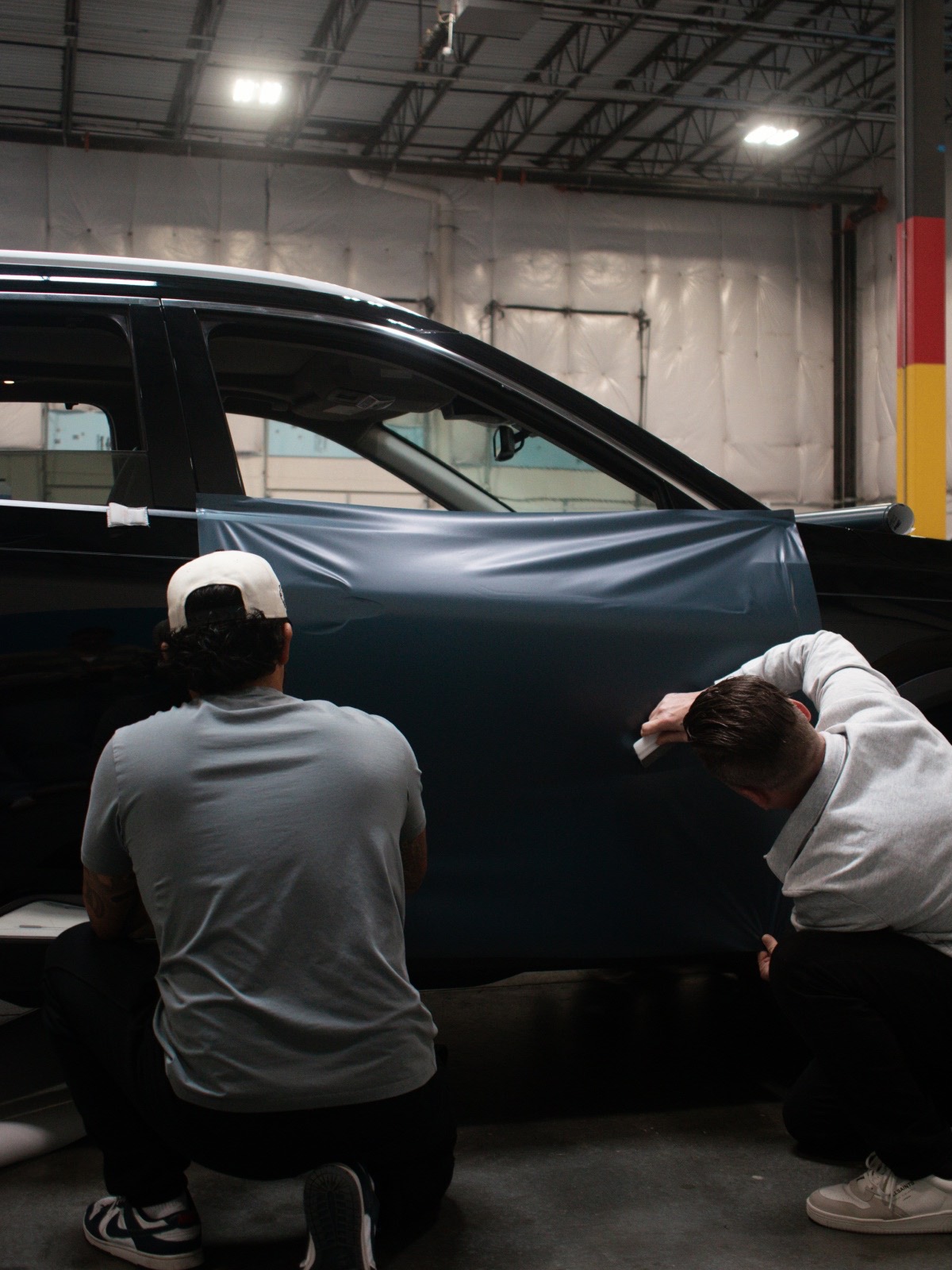 Two installers laying film on a door